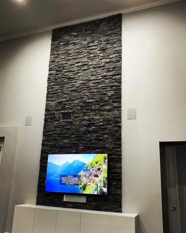 Tall stone fireplace wall with mounted TV